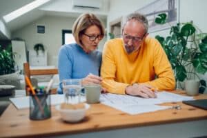 Senior couple sitting at table and looking into blueprints of their new home
